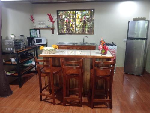 a kitchen with a counter with chairs and a refrigerator at FINCA La PAZ - Sarapiqui in Puerto Viejo