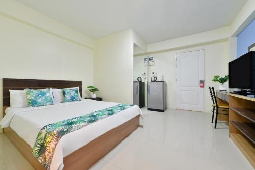 Schlafzimmer mit einem Bett und einem Flachbild-TV in der Unterkunft Salin Home Hotel Ramkhamhaeng in Bangkok