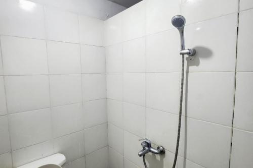 a shower in a white tiled bathroom at WSL Hotel Mitra Reddoorz in Jodoh