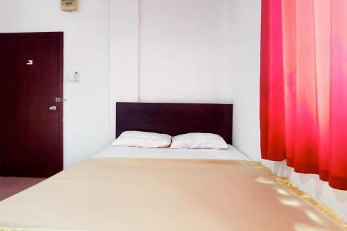 a bedroom with a large bed with red curtains at WSL Hotel Mitra Reddoorz in Jodoh