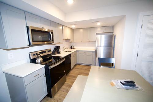 a kitchen with white cabinets and a stainless steel refrigerator at The Lenny: Modern Boutique Loft in Washington, D.C.