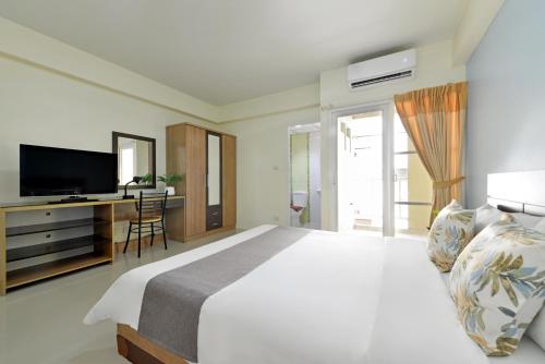 a bedroom with a bed and a desk with a television at Salin Home Hotel Ramkhamhaeng in Bangkok