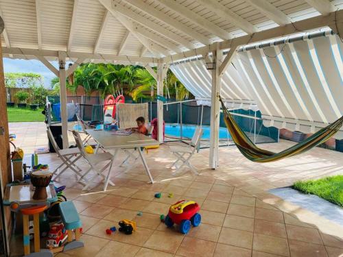 a patio with a hammock and a table and a child at Villa Morne-Bou in Petit-Bourg