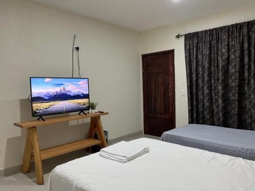 Habitación con 2 camas y mesa con TV. en Posada Ceibamar Chichen Itzá en Pisté
