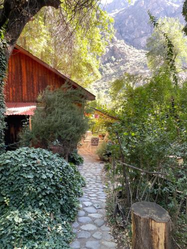 a stone path next to a house with a mountain at Cabaña alpina en plena cordillera con acceso a Río in Río Blanco