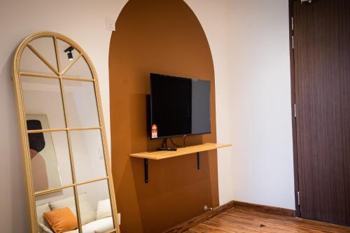a room with a tv on a wall with a mirror at K Avenue by Pinstay in Donggongon
