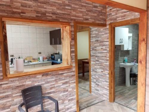 een kamer met een bakstenen muur met een stoel en een keuken bij Hermosa casa - Cajon del Maipo in El Canelo