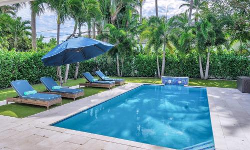 una piscina con sillas y sombrilla en The Sapphire Villa - LUX 5 Bed en West Palm Beach