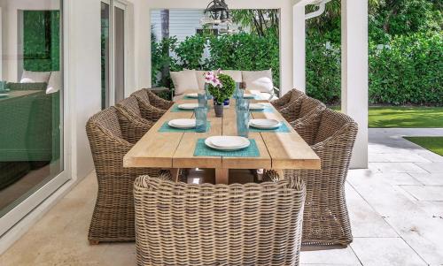 una mesa de madera con sillas de mimbre en el patio en The Sapphire Villa - LUX 5 Bed en West Palm Beach