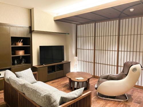 a living room with a couch and a chair and a television at Keiryuso Siorie in Matsumoto