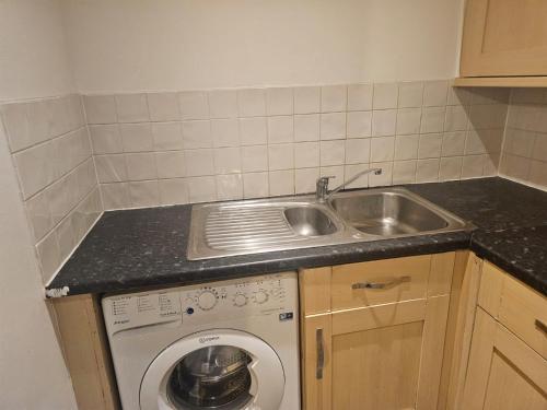 a kitchen with a sink and a washing machine at Big double room with bathroom in 2 bedroom flat kitchen is shared in Harrow on the Hill