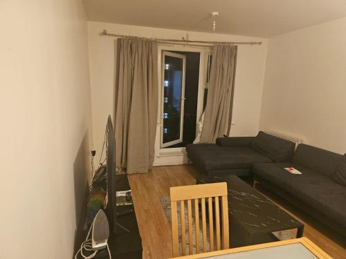 a living room with a couch and a tv at Big double room with bathroom in 2 bedroom flat kitchen is shared in Harrow on the Hill