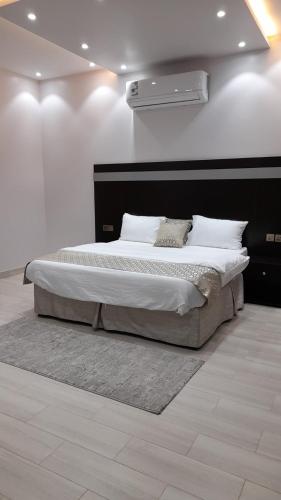 a bedroom with a large bed with a white wall at فلل ومسابح بلوسكاي الباحه-العقيق فله من ثلاث غرف نوم in Al Aqiq