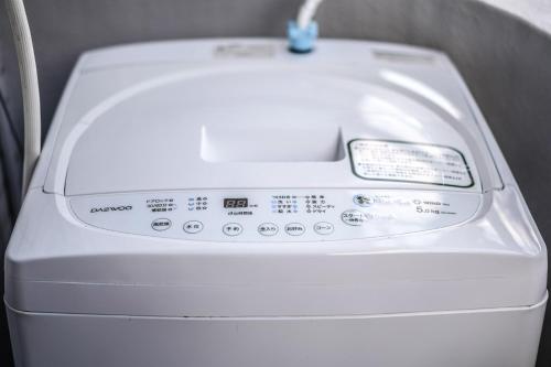 a white washing machine sitting next to a wall at 龙猫民宿-梅田店201 in Osaka