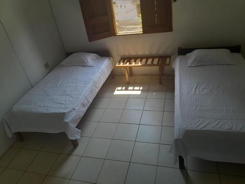 2 Betten in einem kleinen Zimmer mit Fenster in der Unterkunft Sarita's House in Esterillos Este