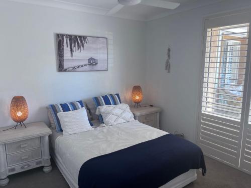 a bedroom with a bed and two lamps and a window at Toowoon Bay - Private Pool - Outside Shower in Long Jetty