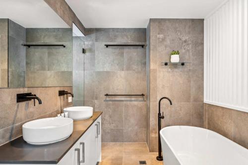 a bathroom with two sinks and a bath tub at 'Bonnyview' Elegant 4-Bed Home By the Beach in Marcoola