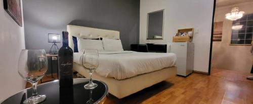 a bedroom with a bed and two wine glasses on a table at Glow Boutique Hotel Zona G in Bogotá