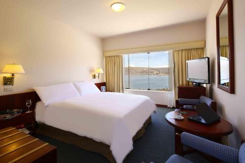 a hotel room with a large bed and a window at GHL Hotel Lago Titicaca in Puno