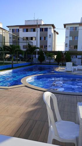 une chaise blanche assise à côté de la piscine dans l'établissement Aconchego da Barra, à Barra dos Coqueiros