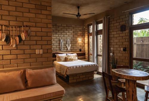 a bedroom with a bed and a brick wall at Villa Macarena Apartamentos Boutique - Adults Only in Puerto Escondido