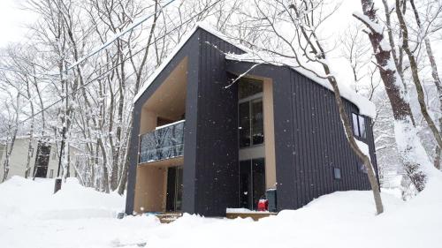 a black house in the snow in the woods at soil Hakuba in Hakuba