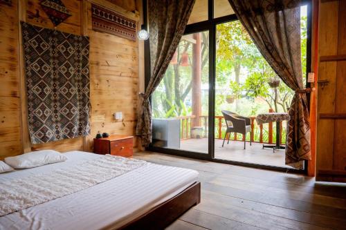 a bedroom with a bed and a balcony with a table at La Vie En Rose Ba Vì Homestay in Hanoi