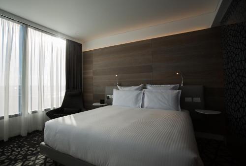 a hotel room with a bed and a large window at Pullman Sydney Airport in Sydney