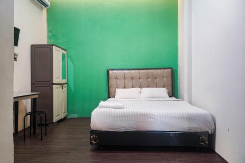 a bed in a room with a green wall at RedDoorz Syariah near Universitas Jambi Telanaipura in Jambi