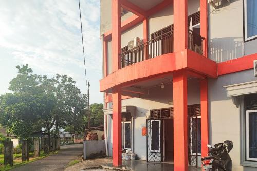 a red and white building with a balcony at RedDoorz Syariah near Universitas Jambi Telanaipura in Jambi