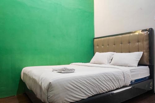 a bedroom with a bed with a green wall at RedDoorz Syariah near Universitas Jambi Telanaipura in Jambi