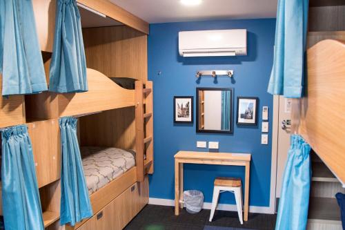 um quarto com beliches, uma mesa e um espelho em Adventure Q2 Hostel em Queenstown