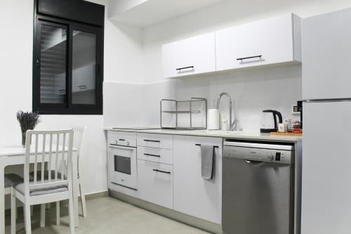 a kitchen with white cabinets and a chair in it at Luxury Family Apartment #26 By Hashdera Eilat in Eilat