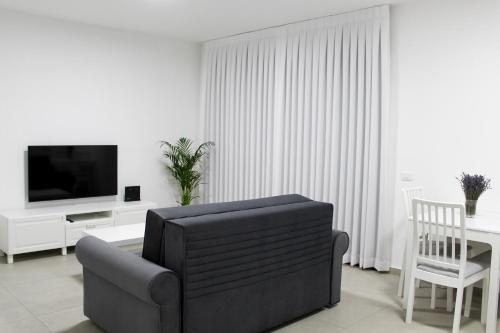 a living room with a couch and a television at Luxury Family Apartment #26 By Hashdera Eilat in Eilat