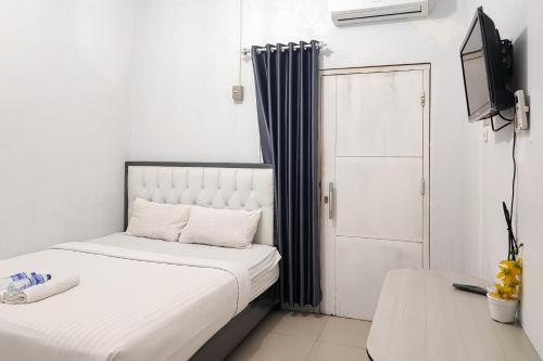 a bedroom with two beds and a tv and a door at RedDoorz Syariah near Lapangan Persijam Jambi in Paalmerah