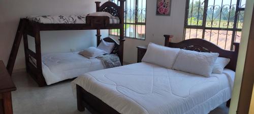 a bedroom with two bunk beds with white sheets at Villa Libertad in Paipa
