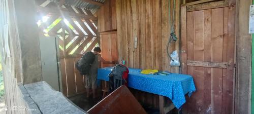 Ein Mann steht in einer Hütte mit einem blauen Tisch. in der Unterkunft Lodging and Adventure in Soposo