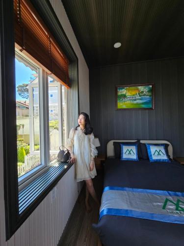 een vrouw die naast een bed in een kamer staat bij Twin Villa Village Đà Lạt in Da Lat