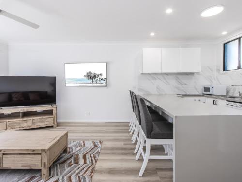 a white kitchen with a large island and a tv at The Laneway Villas by Burleigh Letting Company in Gold Coast