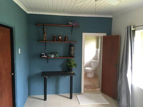 baño con pared azul, mesa y aseo en Ruim gasten verblijf dicht bij zee en Savaneta