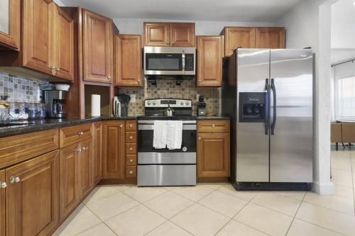 a kitchen with wooden cabinets and a stainless steel refrigerator at Palm Wave Says - Quiet House in Best Area in West Palm Beach