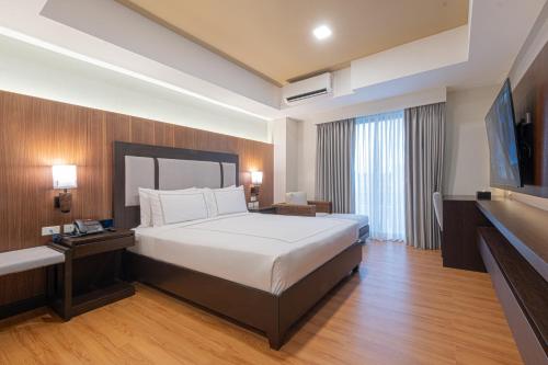 a hotel room with a bed and a flat screen tv at Widus Hotel Clark in Clark