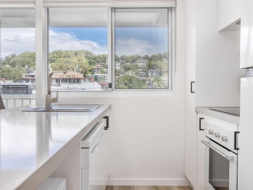 a kitchen with white counters and a window at The Laneway Villas by Burleigh Letting Company in Gold Coast