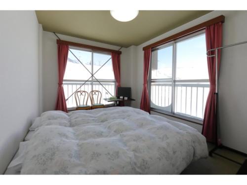 a bedroom with a large bed and two windows at Ishiuchi Ski Center - Vacation STAY 09176v in Seki