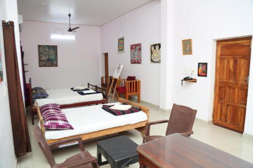 een kamer met 2 bedden en een tafel en stoelen bij Shangrila at blissful haven near to Matrimandir in Auroville
