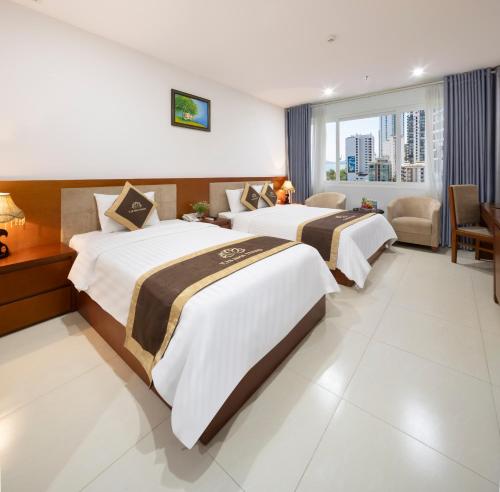 two beds in a hotel room with a window at T78 Nha Trang Hotel in Nha Trang