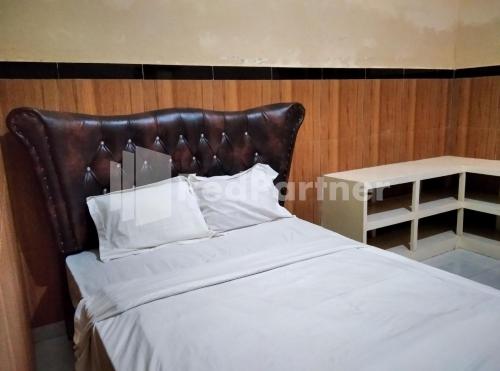 a bed with a leather headboard next to a table at LH101 Guest House Syariah near Makam Sunan Bonang RedPartner in Tuban