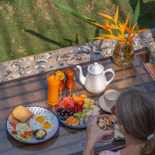 a woman sitting on a table with plates of food at Simroseate in Agonda