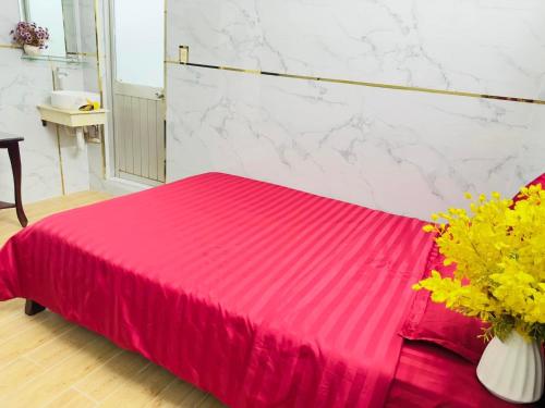 Una cama roja en una habitación con un jarrón de flores en Nhà nghỉ Trung Hiếu 1, en Bình Thủy