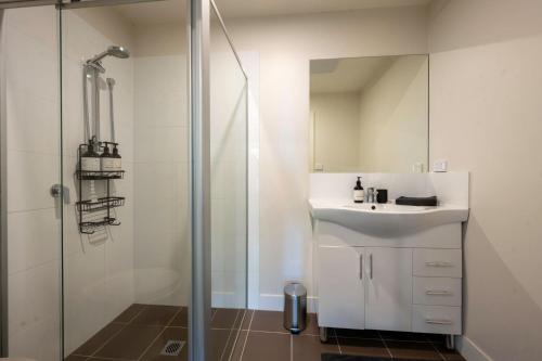 a white bathroom with a sink and a shower at Eastside apartment in Charlestown